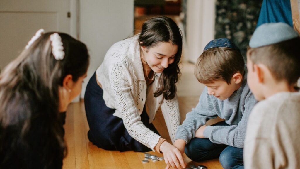 A woman sits playing with children